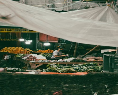 A colorful selection of fresh tropical fruits and green vegetables at an Indonesian traditional market